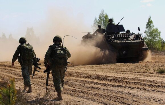 A Lithuanian armoured personnel carrier passes by Canadian soldiers of the Operation REASSURANCE Photo Captain Mark Ruban Public Affairs Officer Operation REASSURANCE Land Task Force