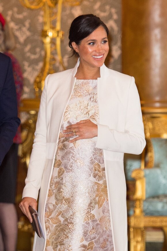 Grįžusi į Bakingamo rūmus, M. Markle puošėsi sidabro spalvos brokato suknele su auksinėmis gėlėmis ir kreminės spalvos „Amanda Wakeley“ paltu